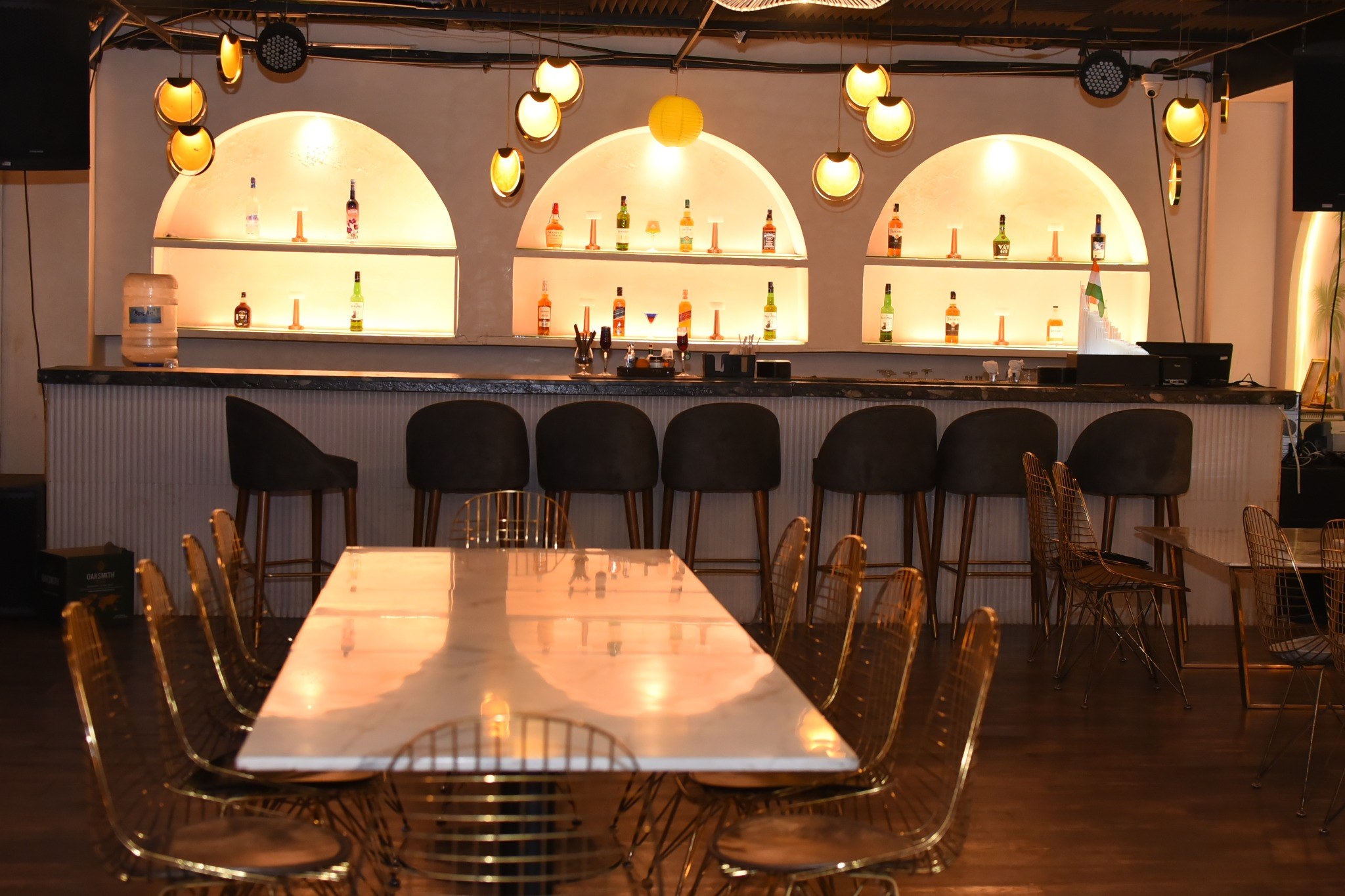 The Commons — a long communal table below the illuminated arches, one floor down